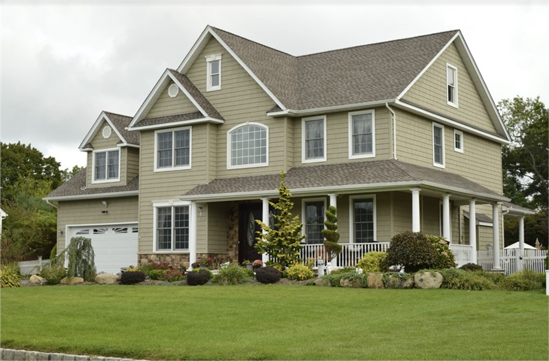 A home with a large front yard and beautifully landscaped gardens.