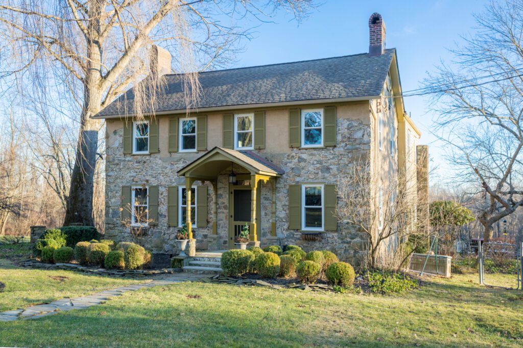 A stone house in the middle of a grassy yard.