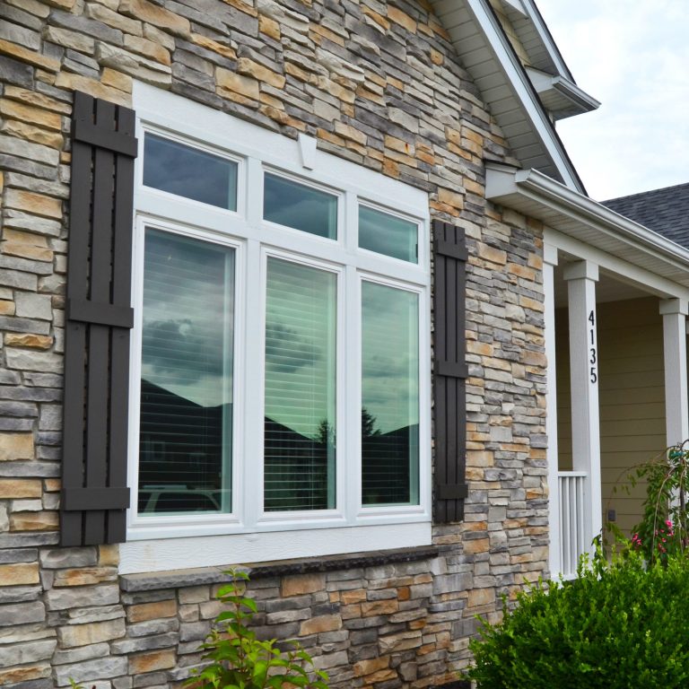 A stone house with a window and shutters, boasting the benefits of home guard windows.