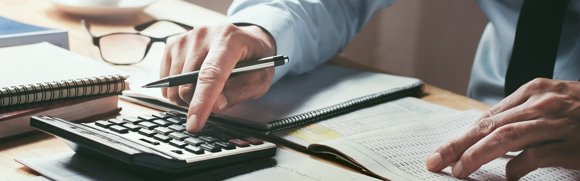 A man is using a calculator on a desk.