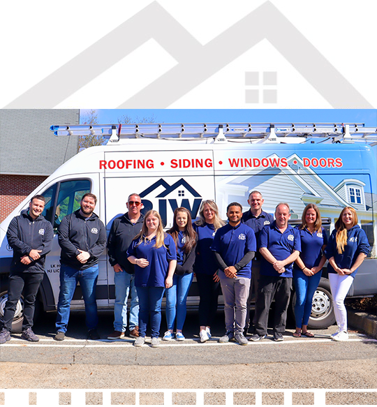 Group of nine people in uniforms standing in front of a company van with roofing, siding, windows, and doors services advertised.