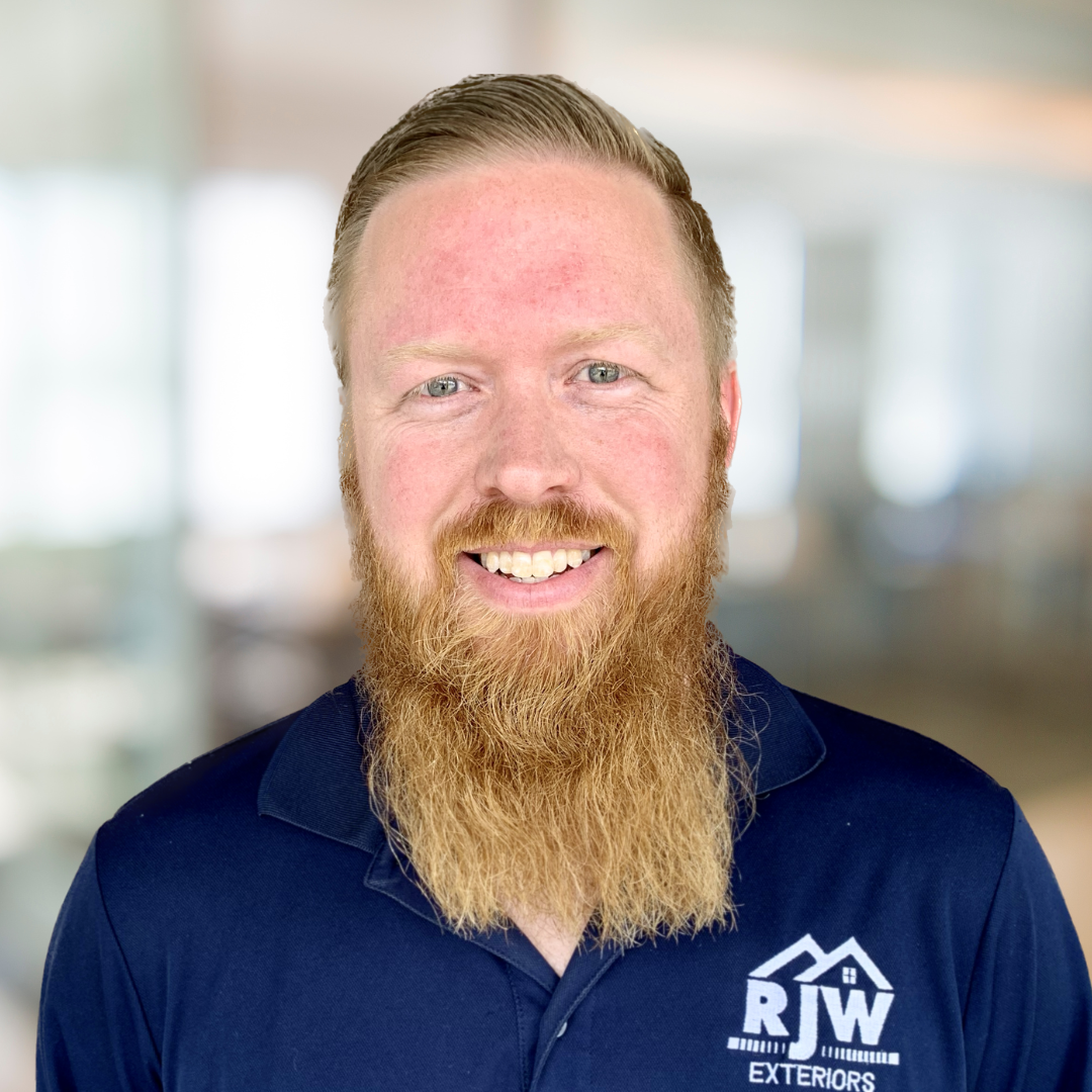A bearded man in a navy blue polo shirt with "RJW Exteriors" logo stands inside a brightly lit room.