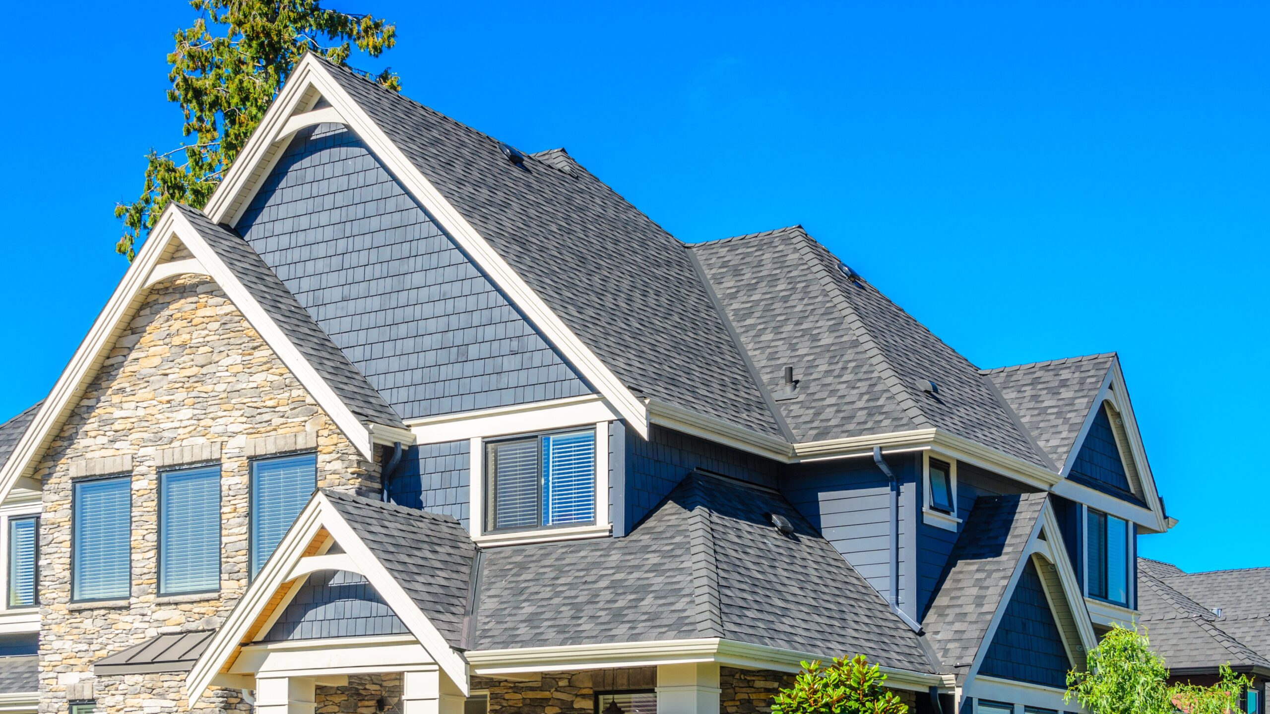 A home with blue and stone siding and a gray shingle roof
