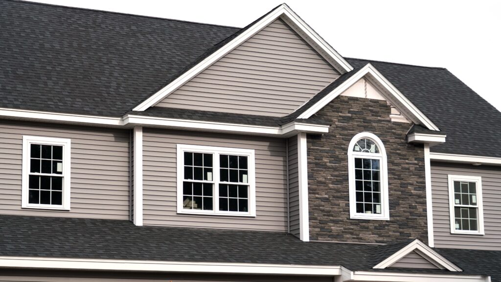 Closeup of the upper floor of a home with newly installed windows that still have the stickers attached