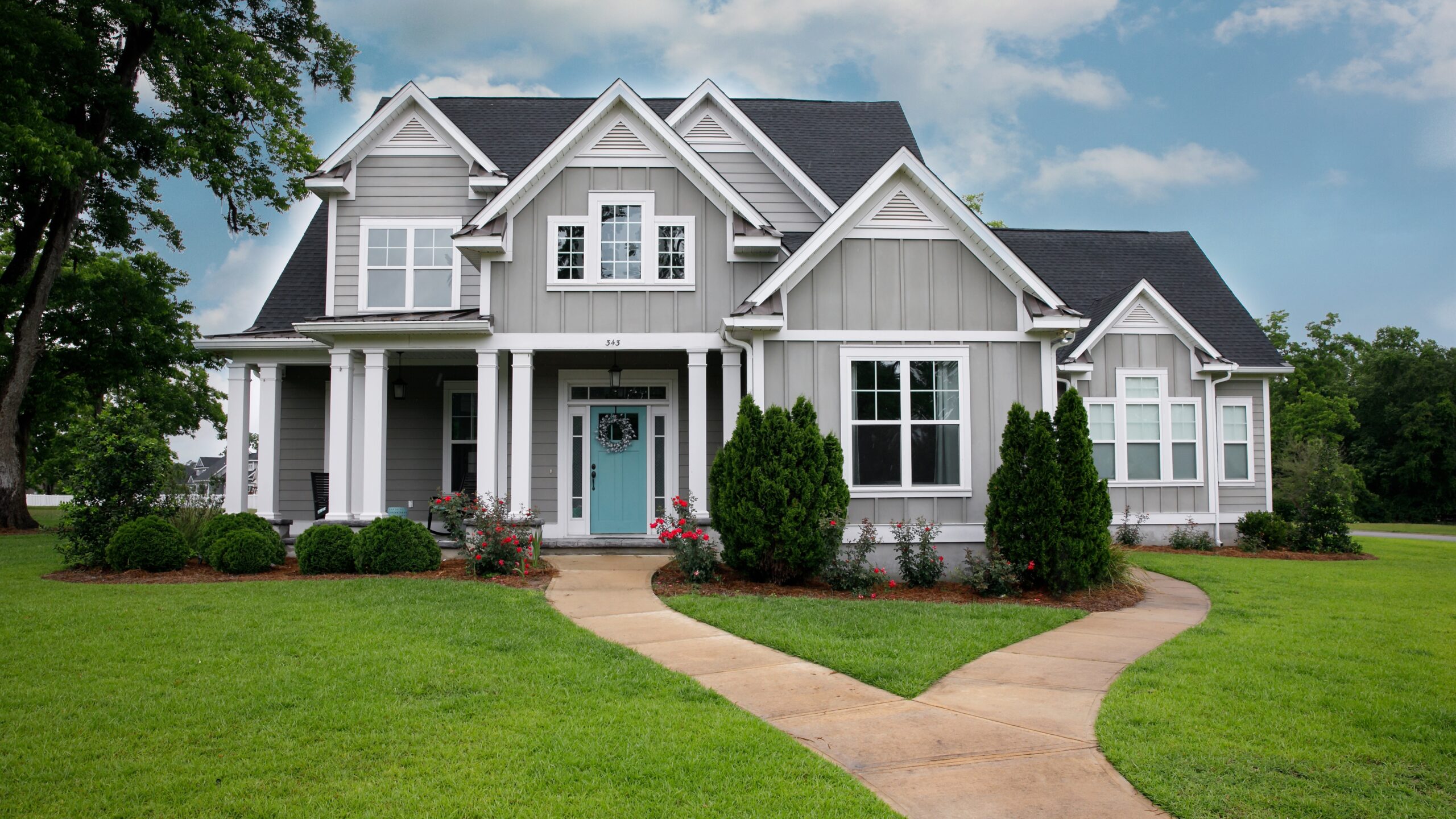 A home with gray James Hardie siding, white trim, a blue entry door, and gray shingle roofing