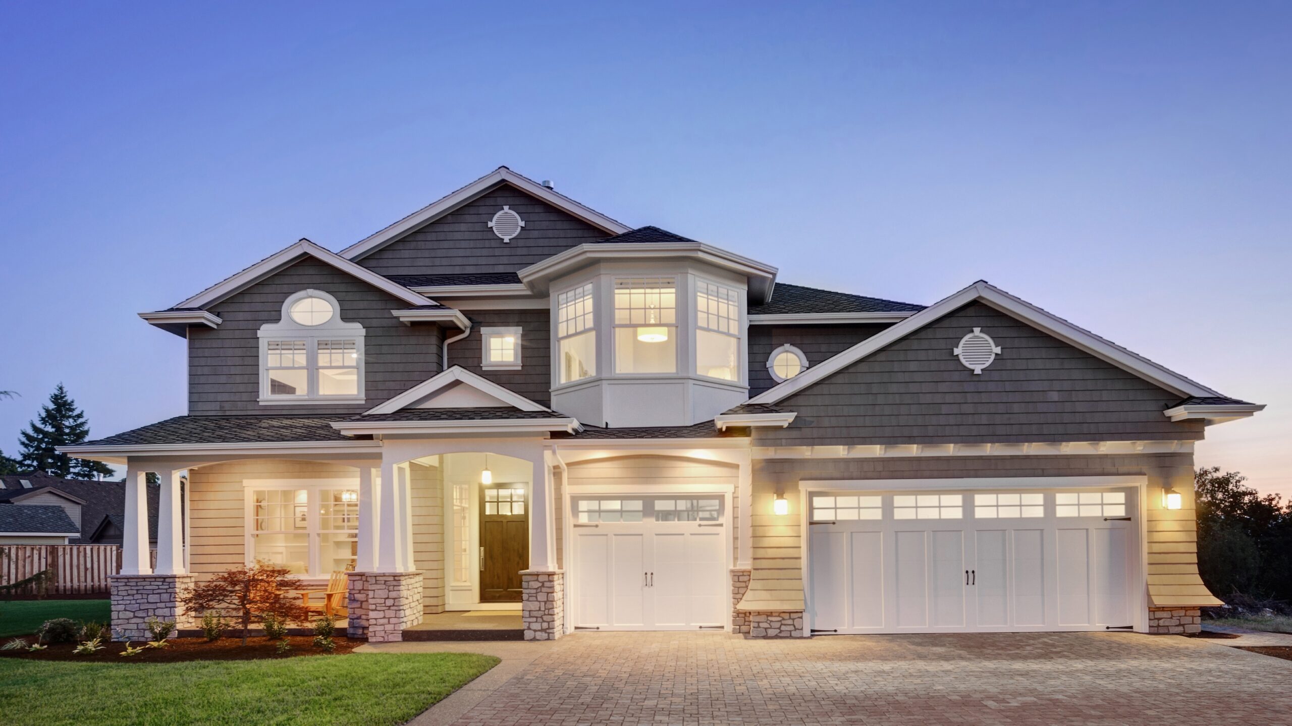 A home with vinyl siding, white trim, and a brown entry door lit up at night