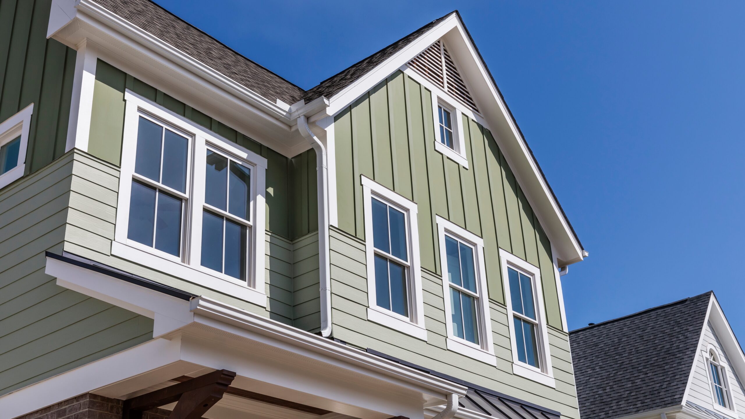 A home with green siding and white replacement windows