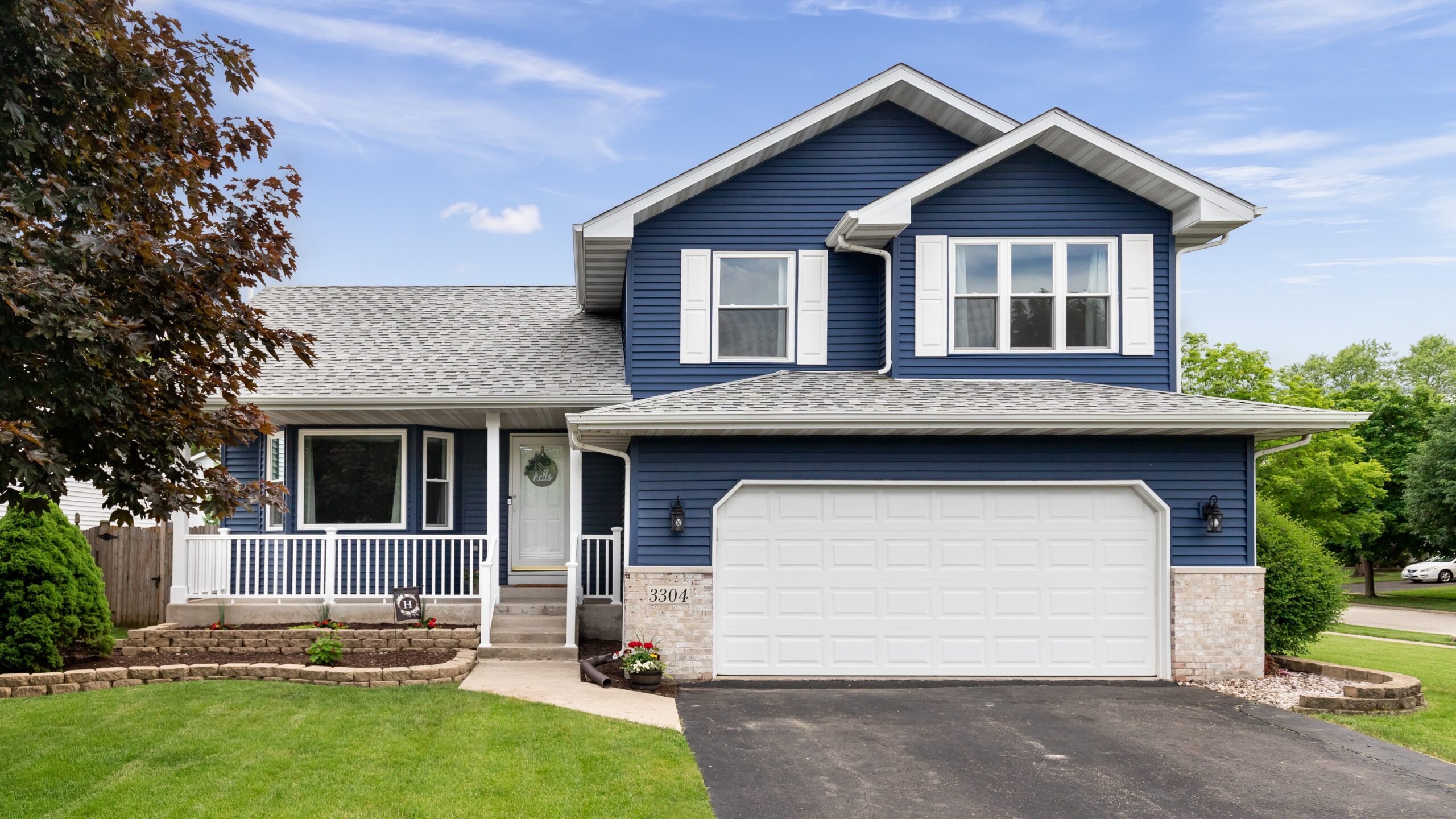 A blue-sided home with white trim and a gray shingle roof