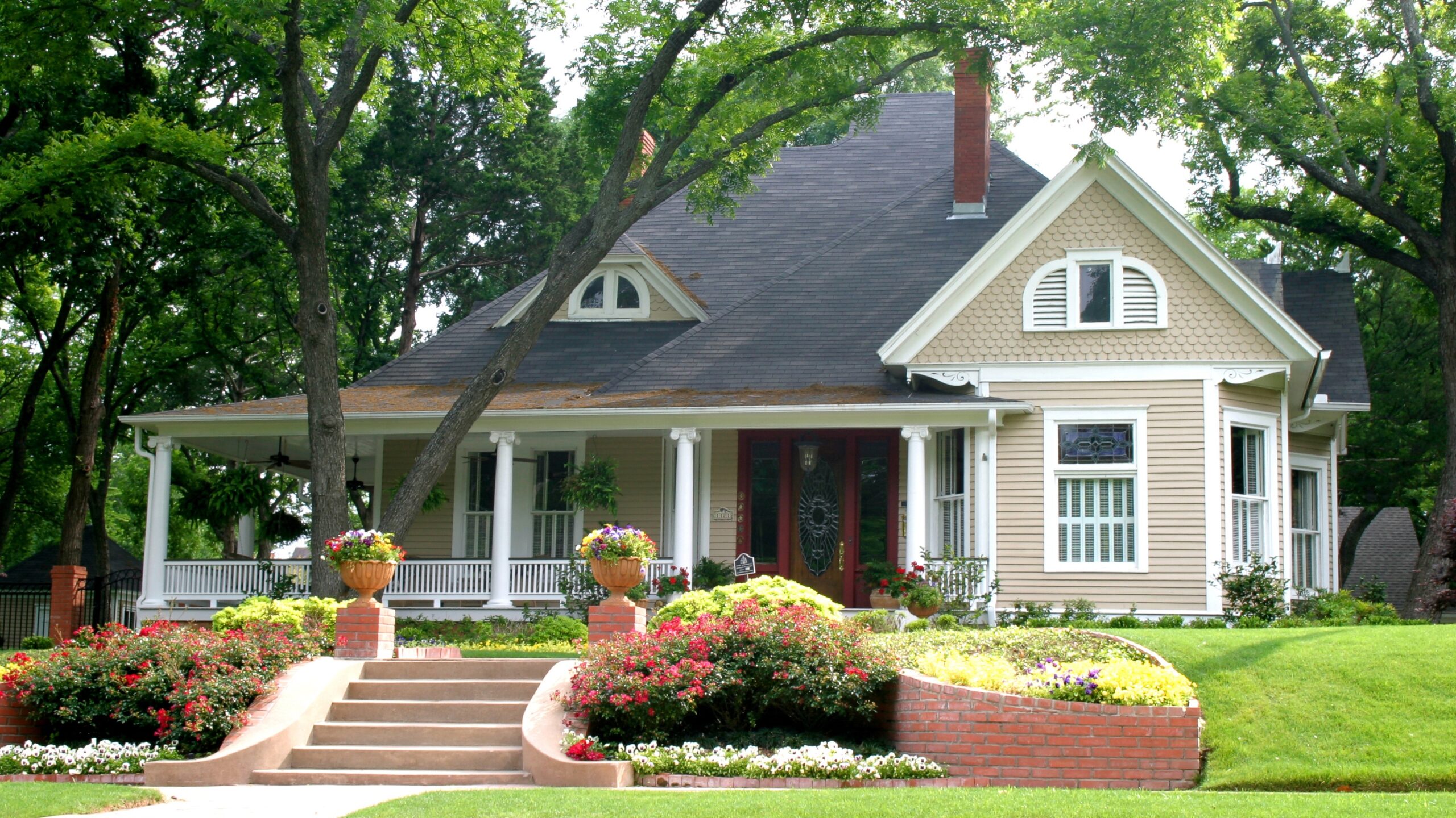 A home with beige siding and white trim surrounded by trees