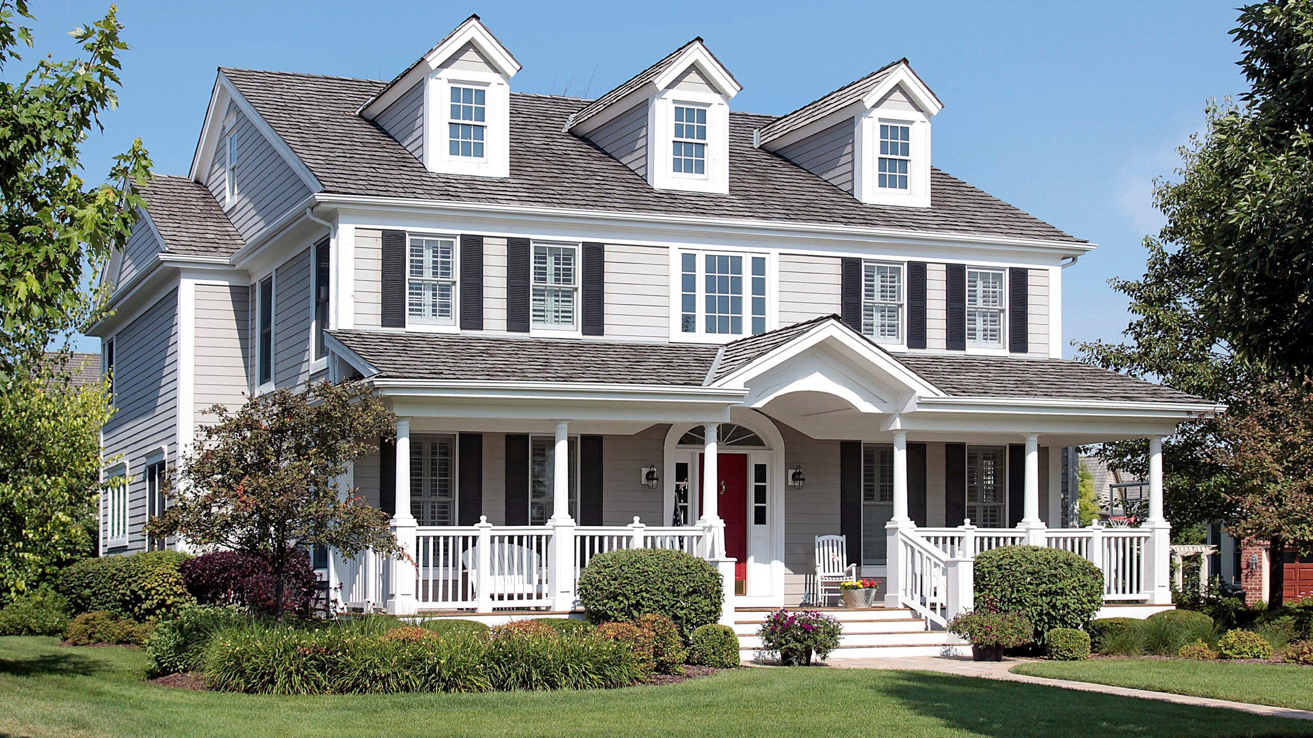 A two-story white-sided home with black shutters and a gray shingle roof