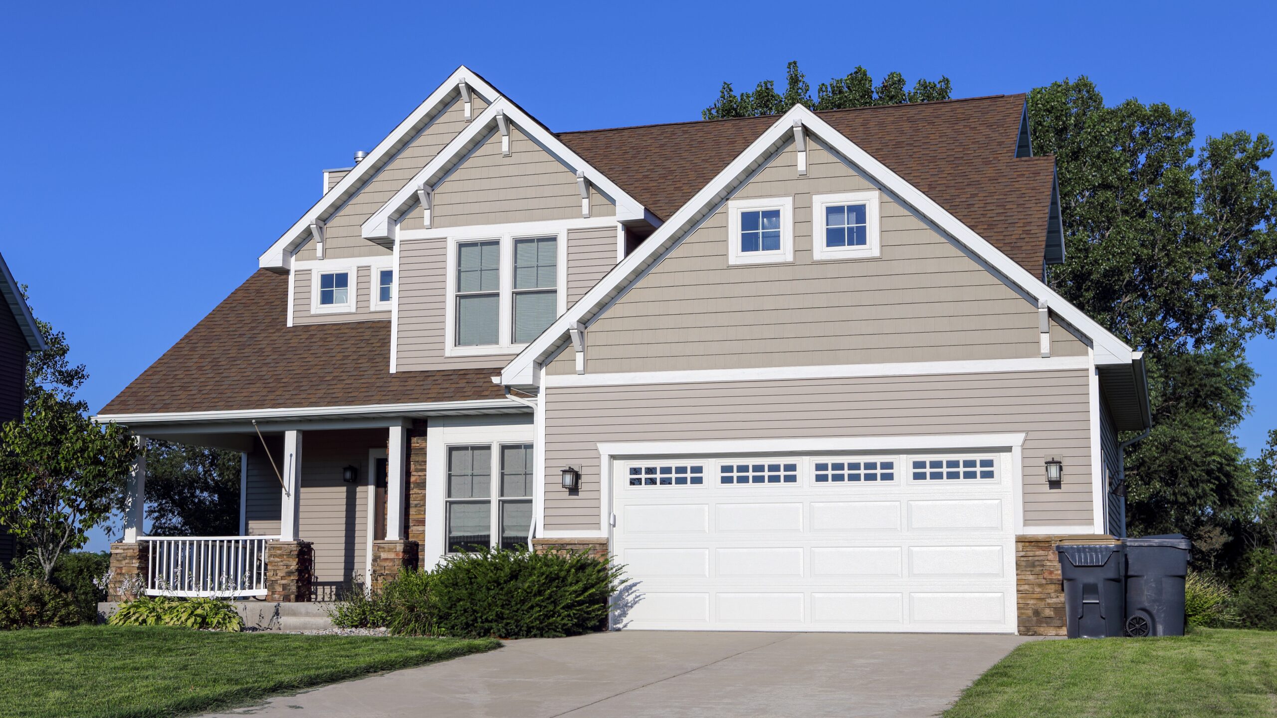 A home with tan siding and a brown shingle roof