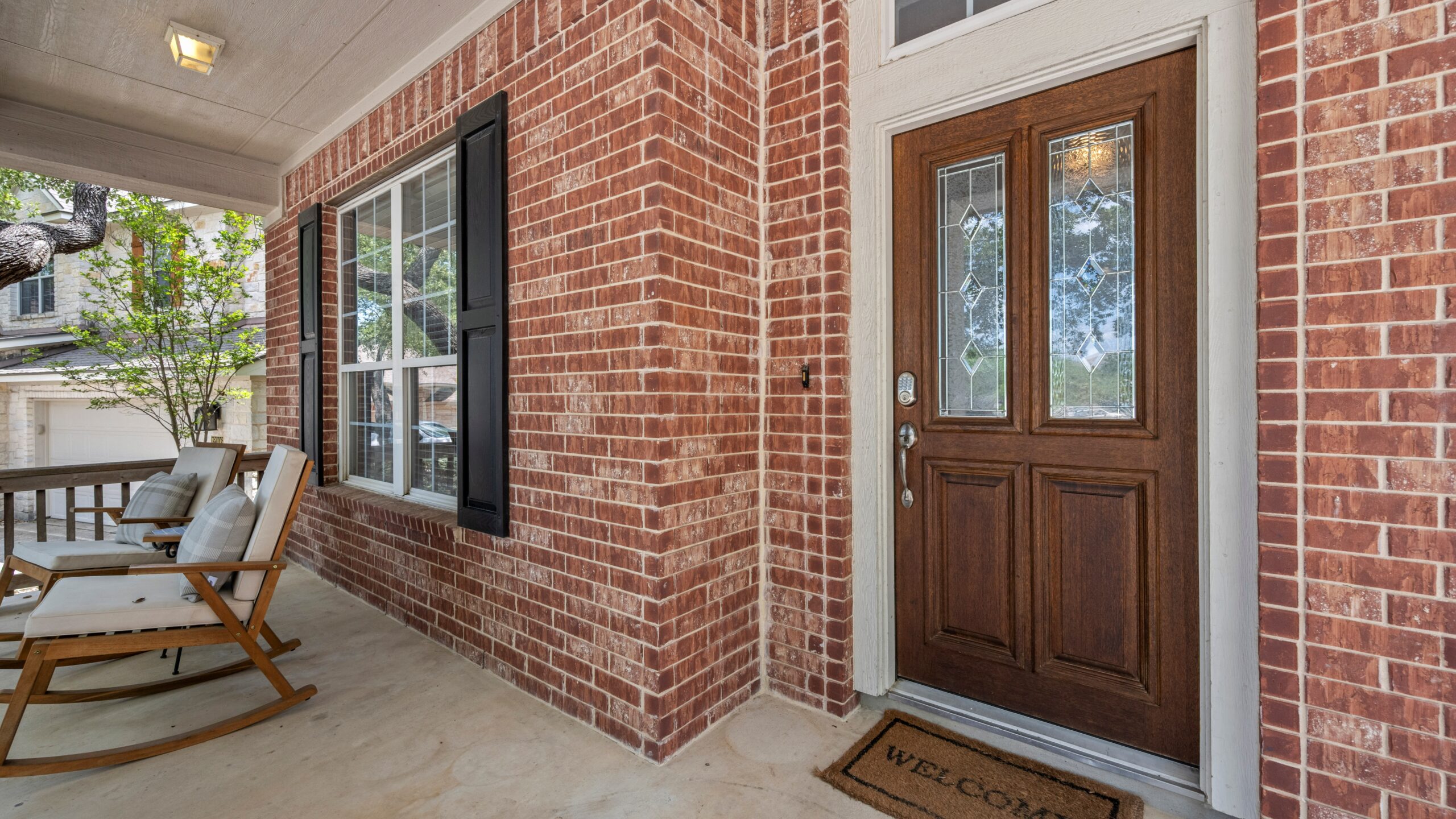 A brick home with a brown entry door with decorative glass inserts