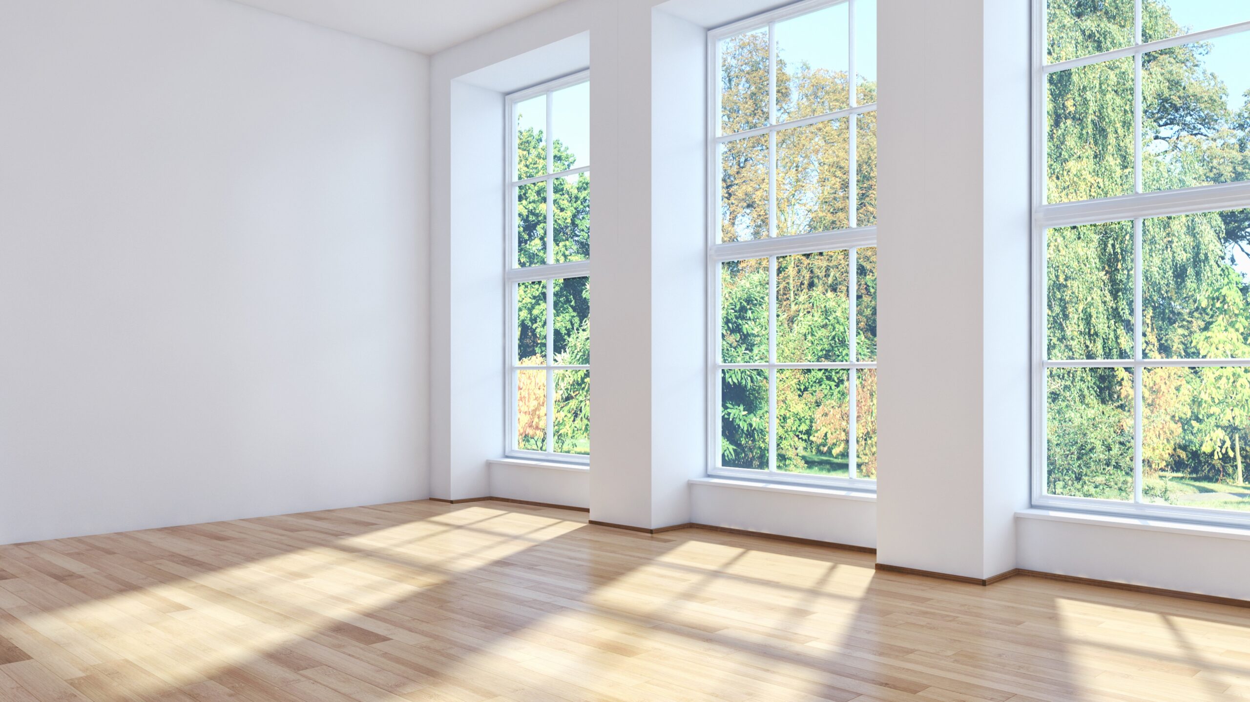 A large empty room with wood floors and three expansive windows