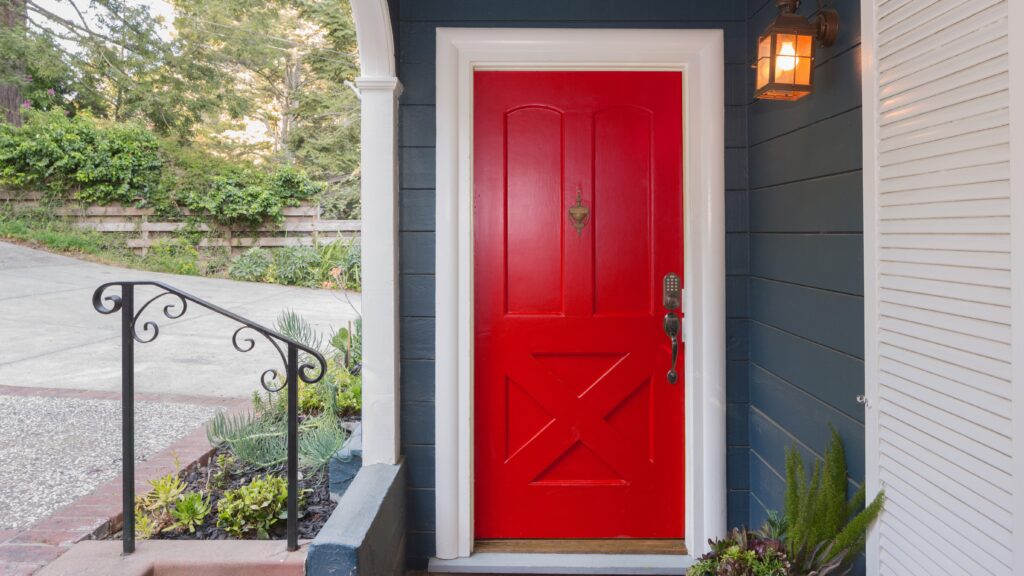 Close view of a bright red front door on a blue house