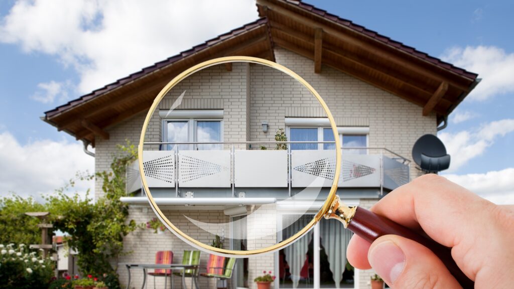 A magnifying glass is held up in front of a two-story home