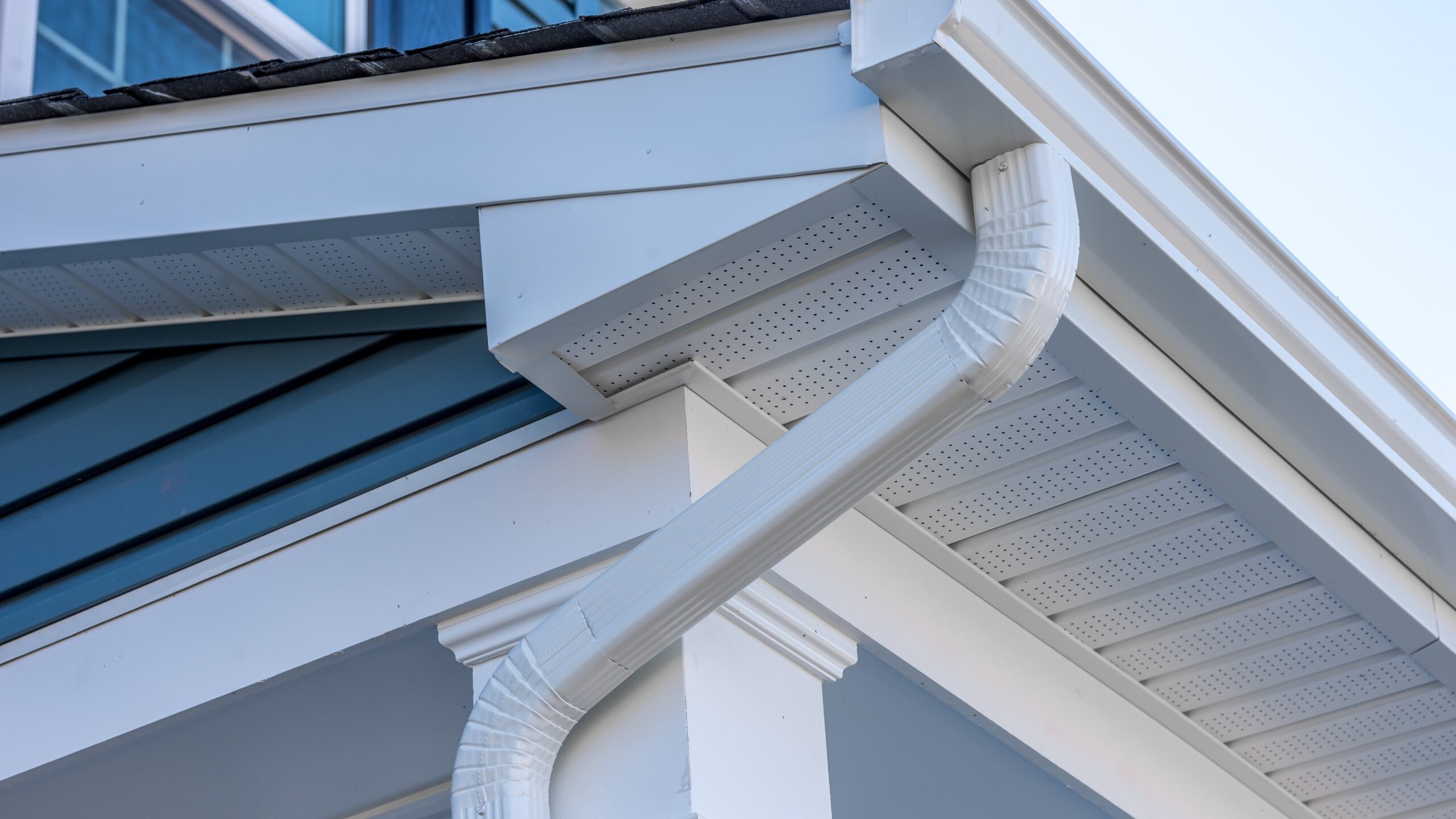 Close upward view of a house corner with soffit, fascia, and gutter