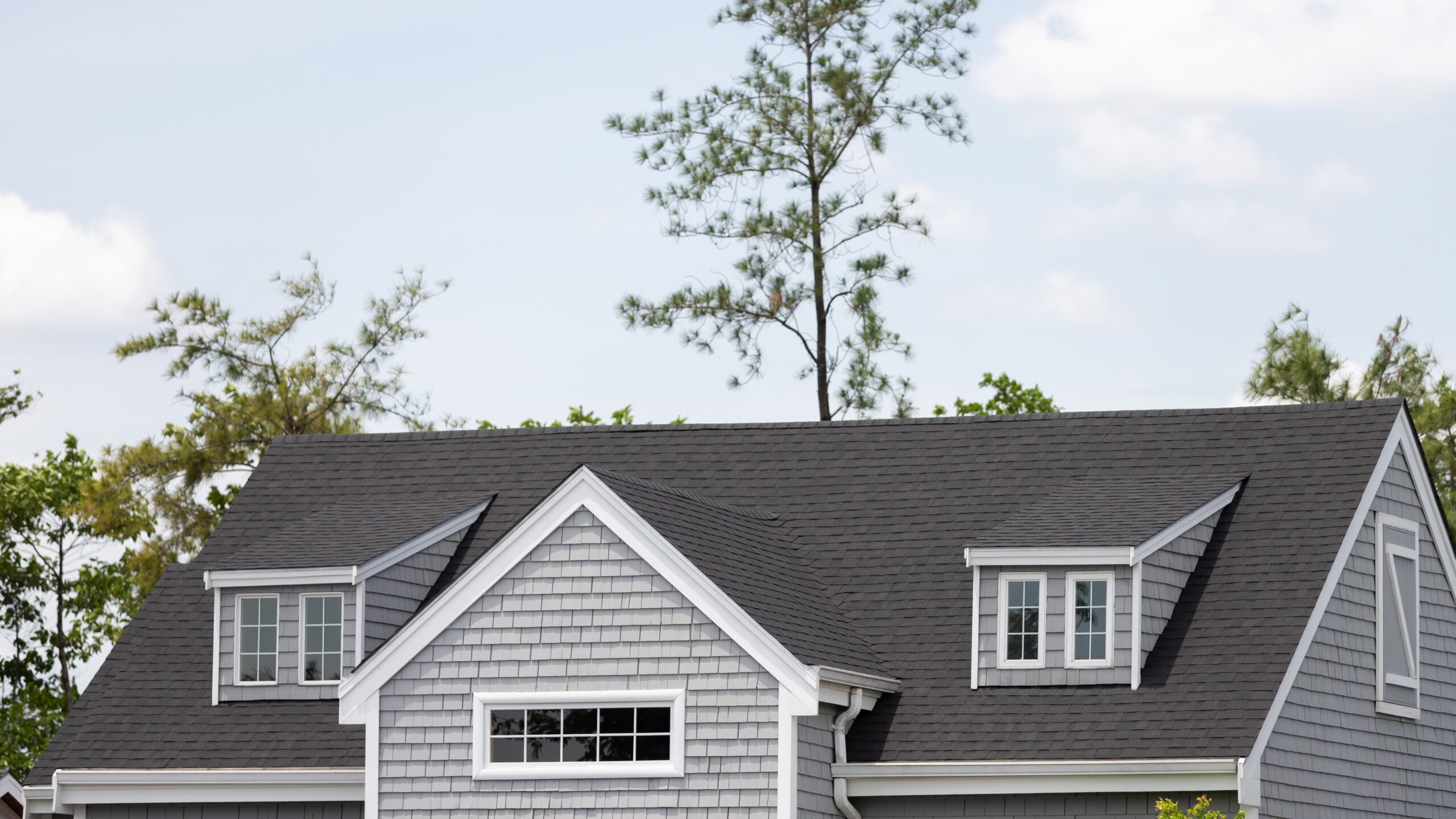 Wide view of a dark gray asphalt roof on a suburban home