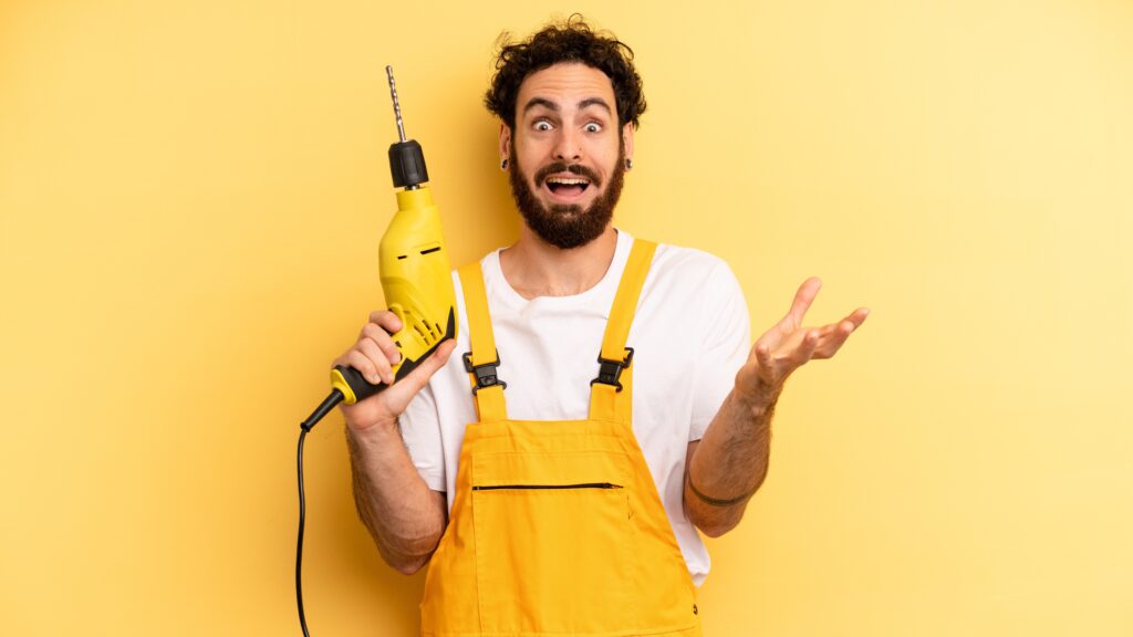 A confused handyman stands with a power drill