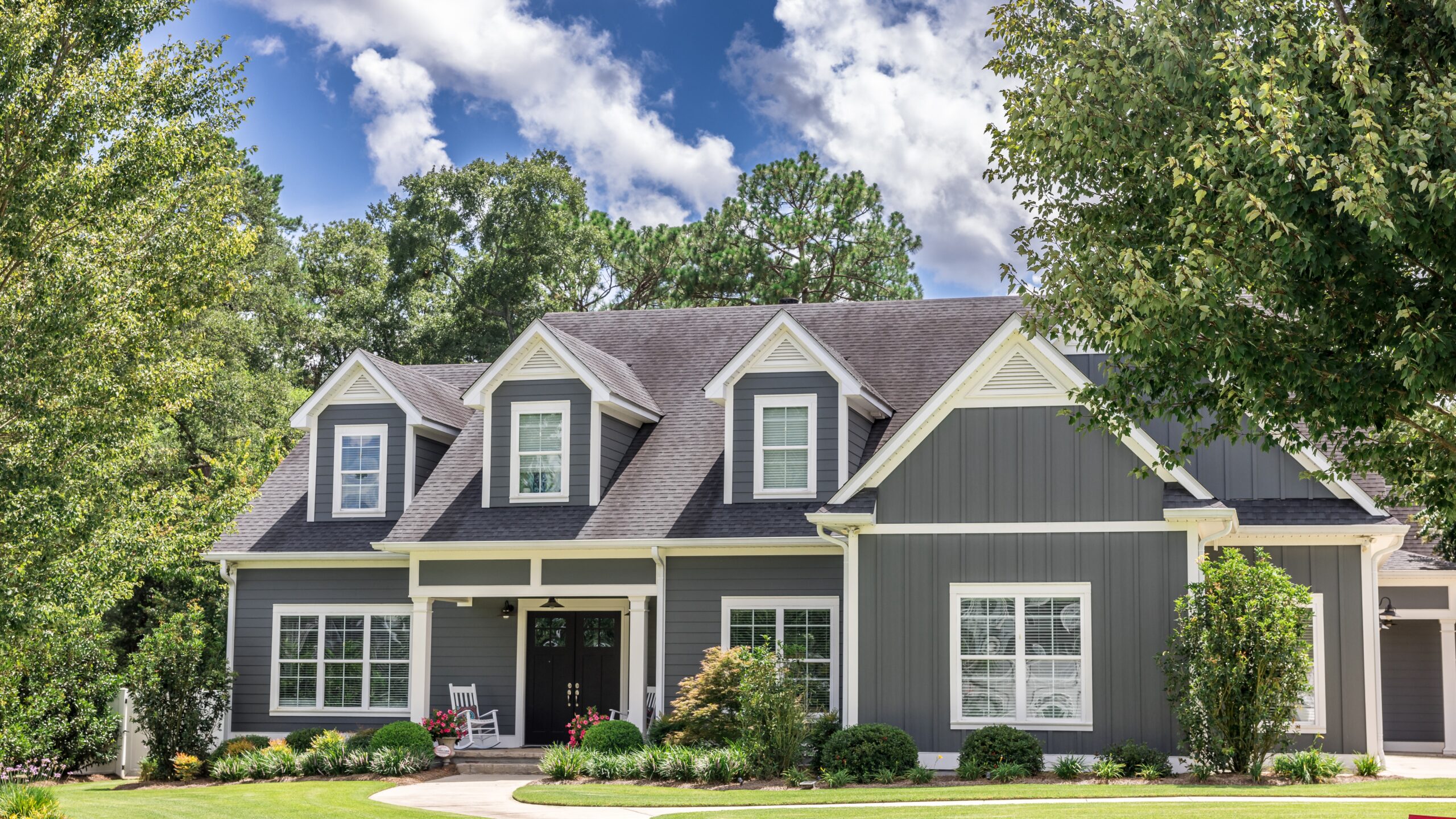 Wide view of a beautiful two-story suburban home clad in grey Hardie Board siding