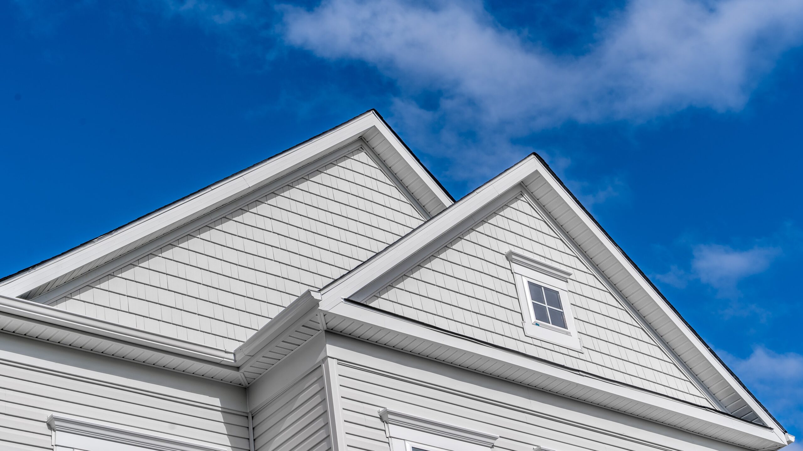 Angled upward view of a gabled two-story home clad in two styles of siding