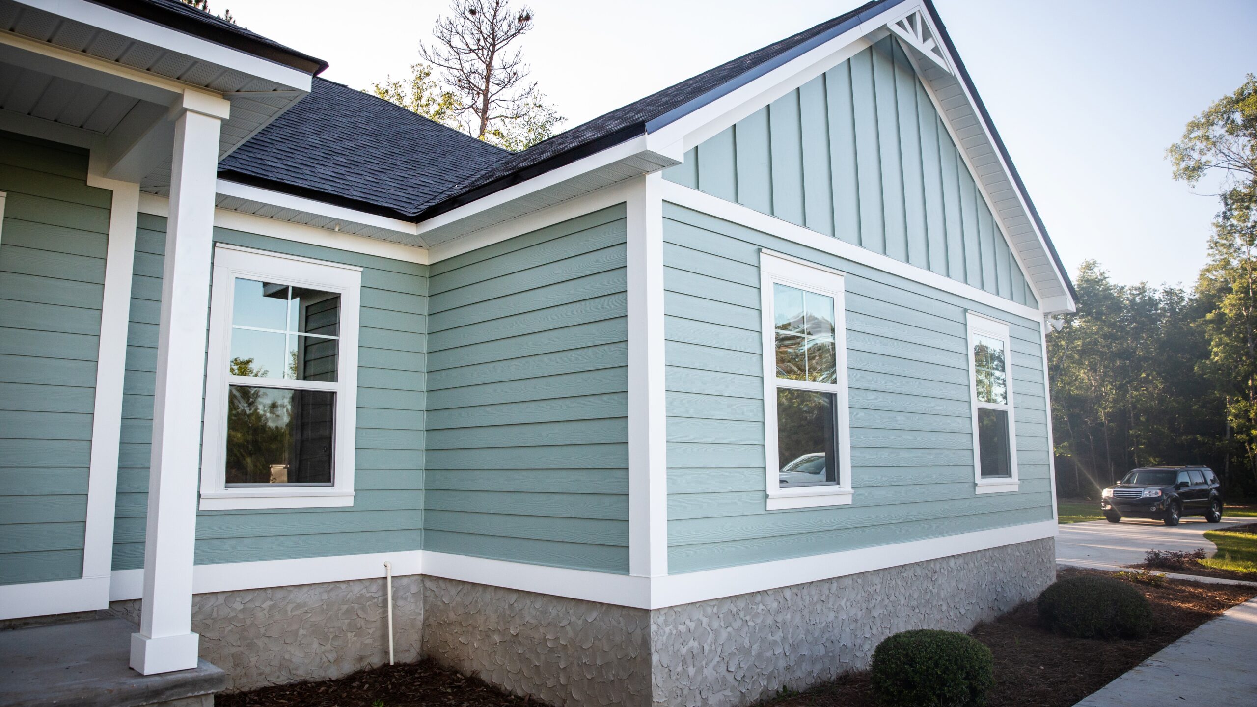 Close, angled view of a gabled one-story home with new siding