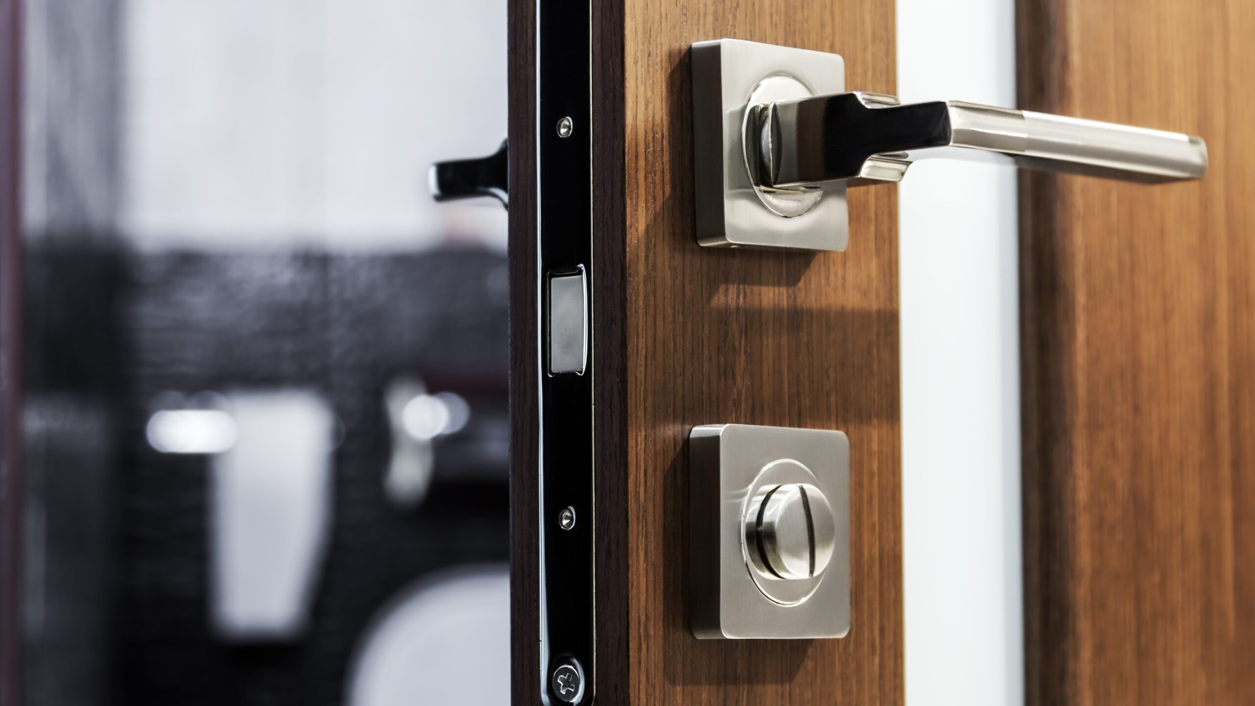 Tight view of the handle and lock of a modern wood and glass front residential door.