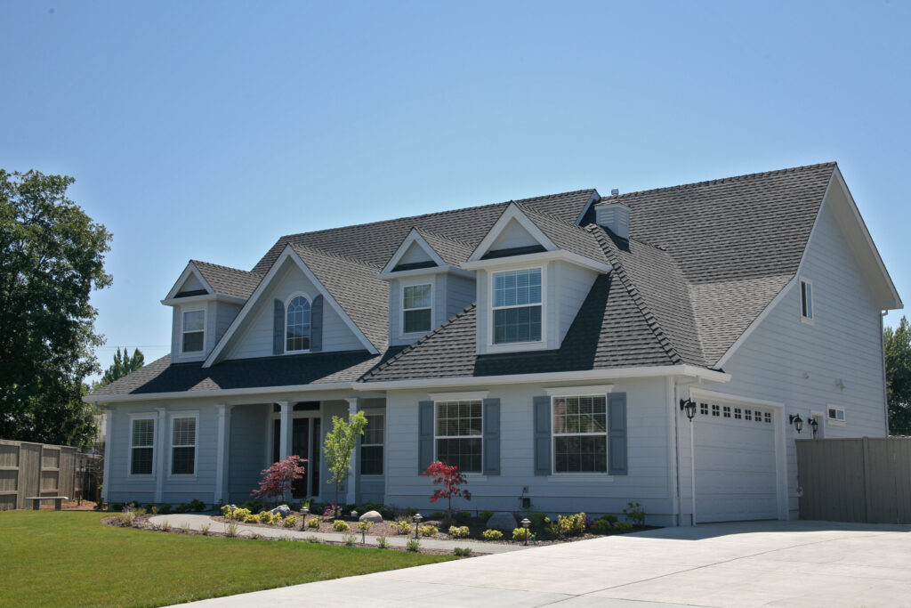 There is a large home with a fresh gray roof