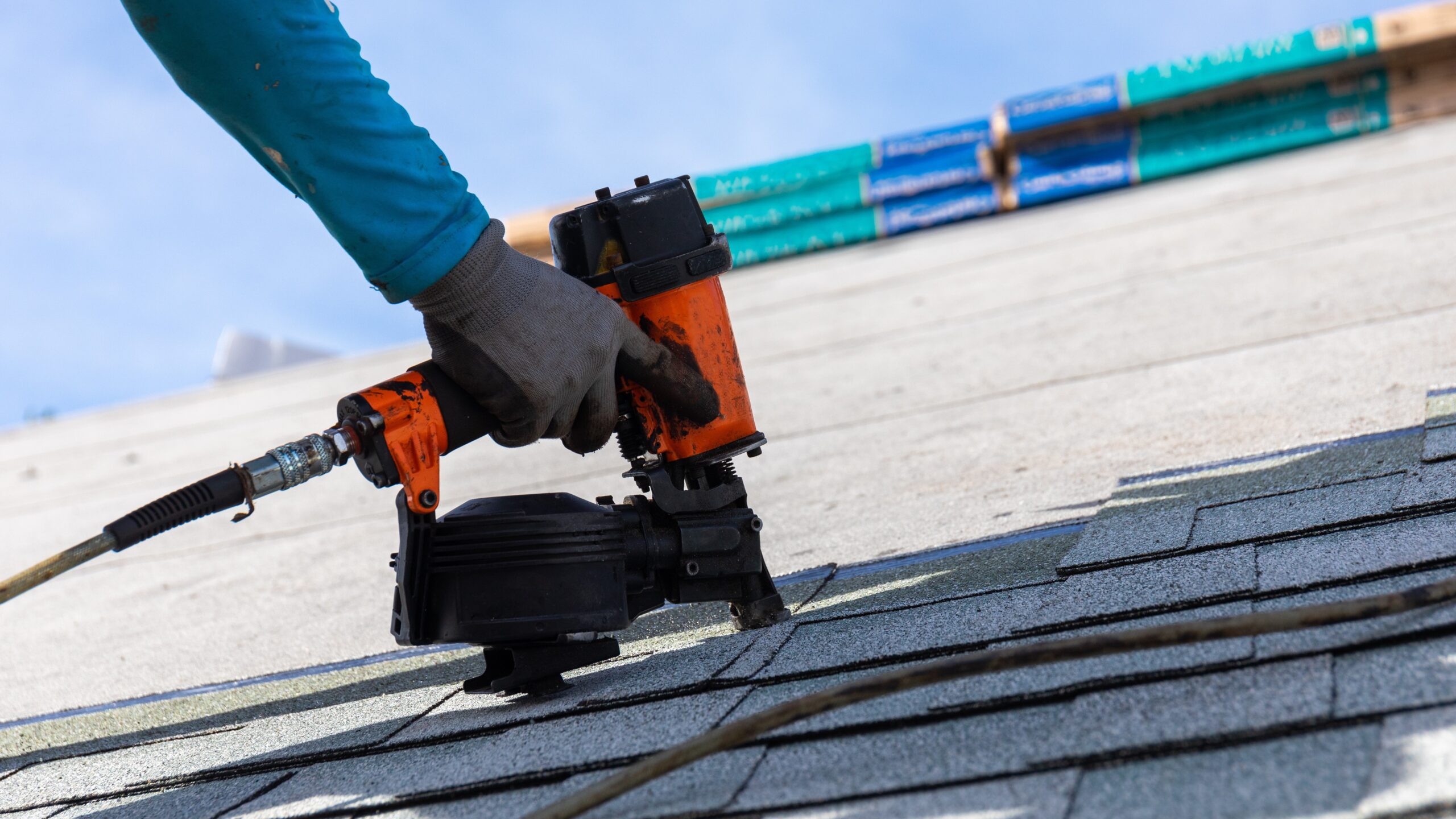 Close view of a roofer nailing shingles into place during a roof replacement