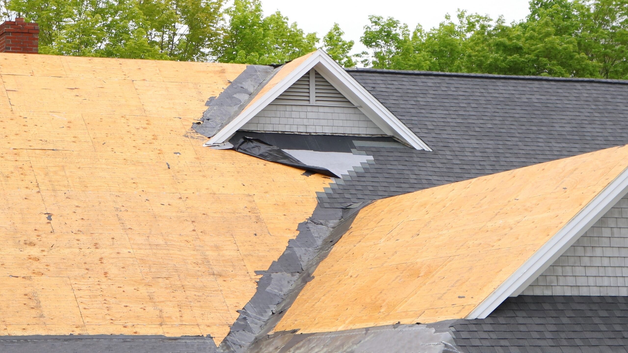 Wide view of a suburban roof with shingle removal in progress