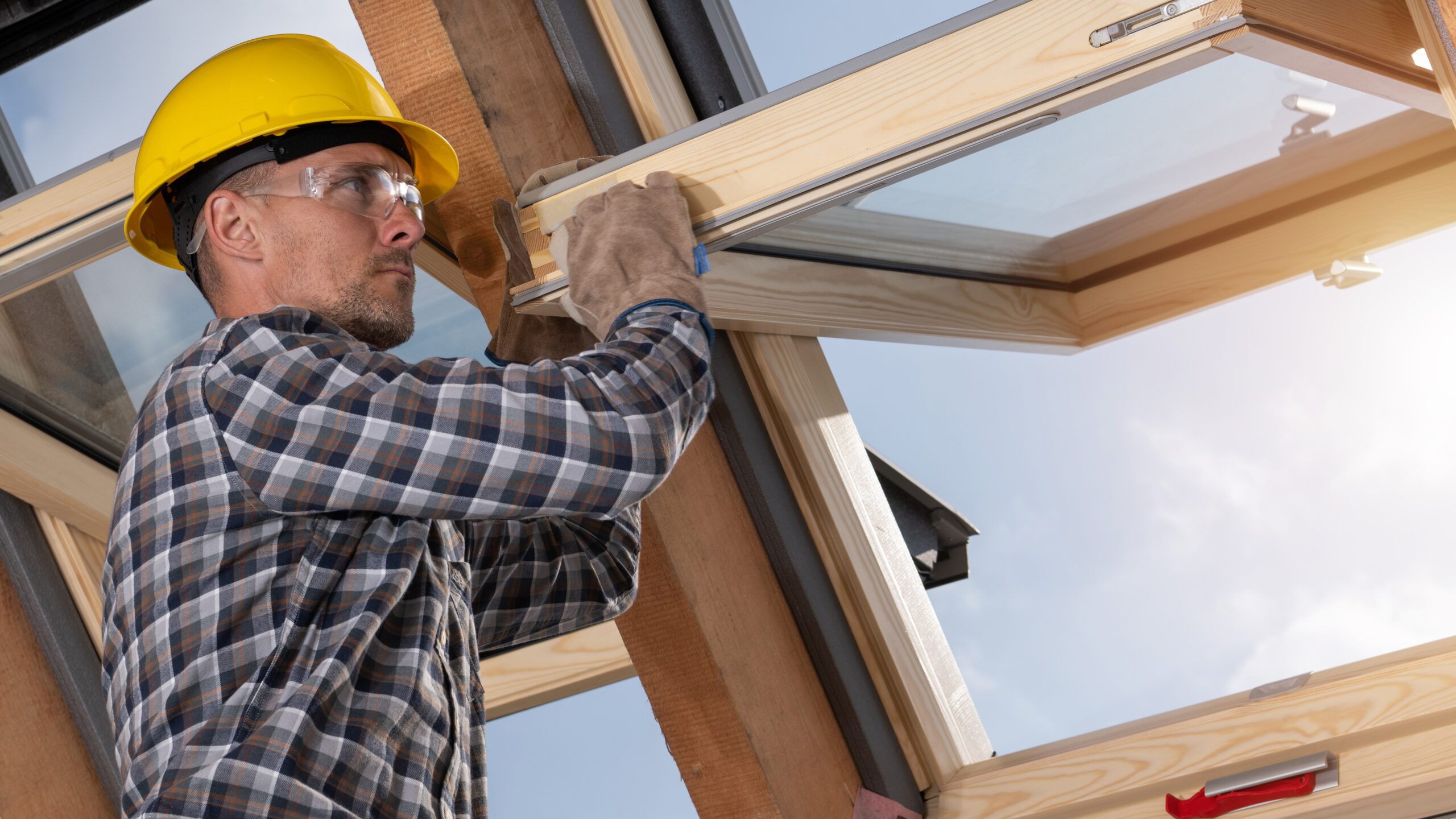 An installer making adjustments on a thick, operable skylight window with a wood frame