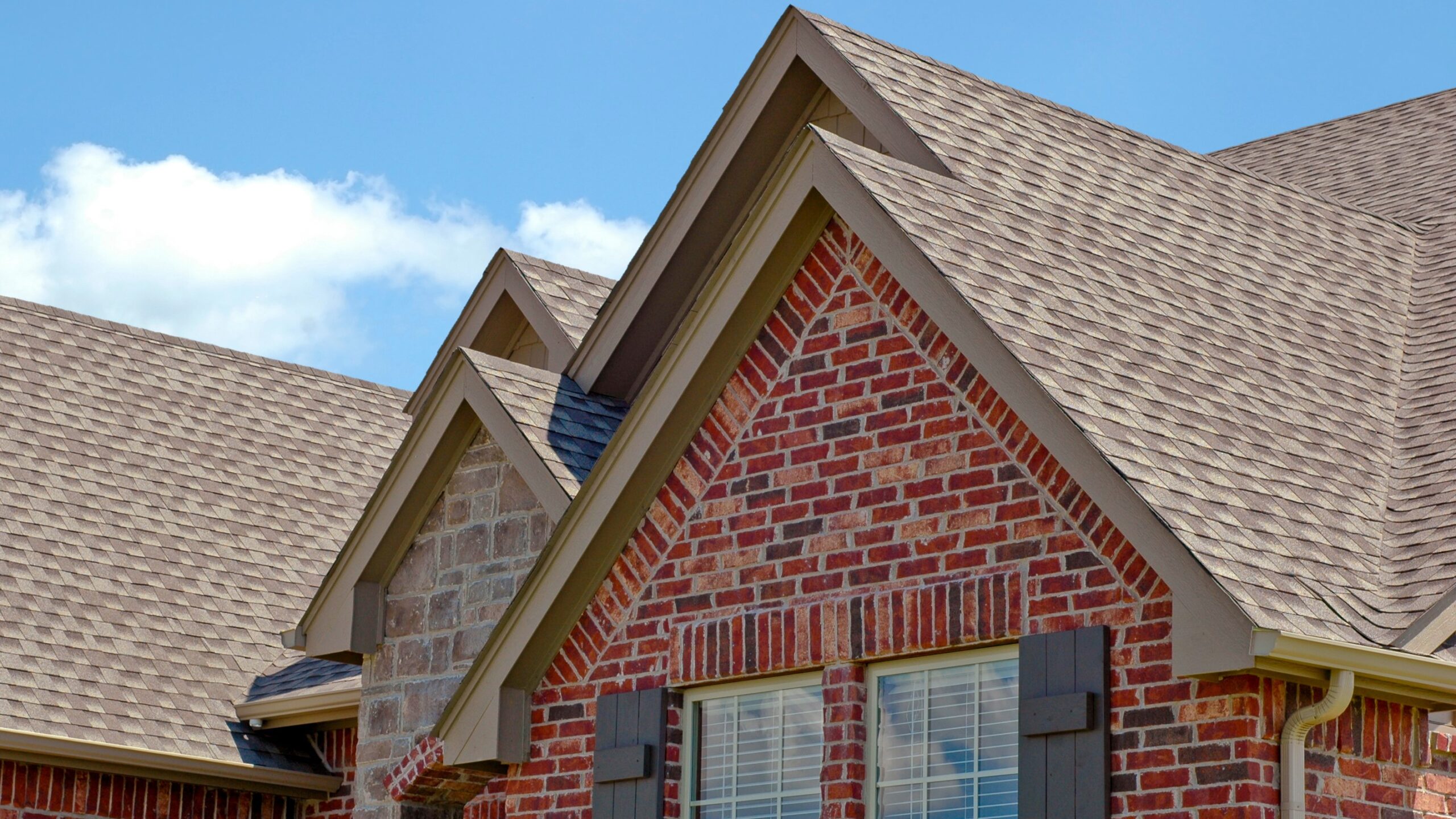 Tight  view of a beautiful asphalt roof installed on a brick suburban home