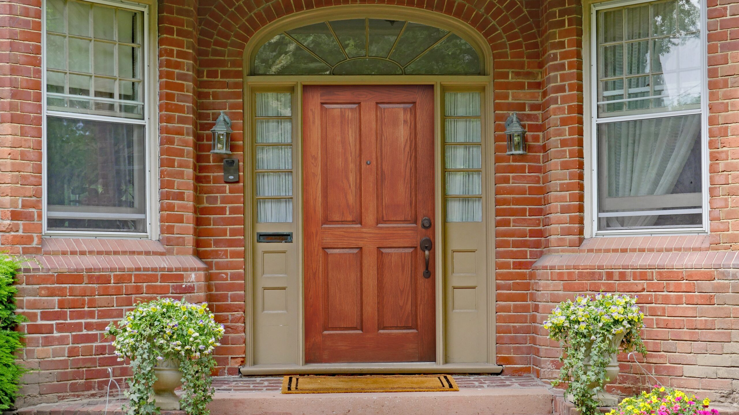 Brick archway entrance with side windows and potted plants