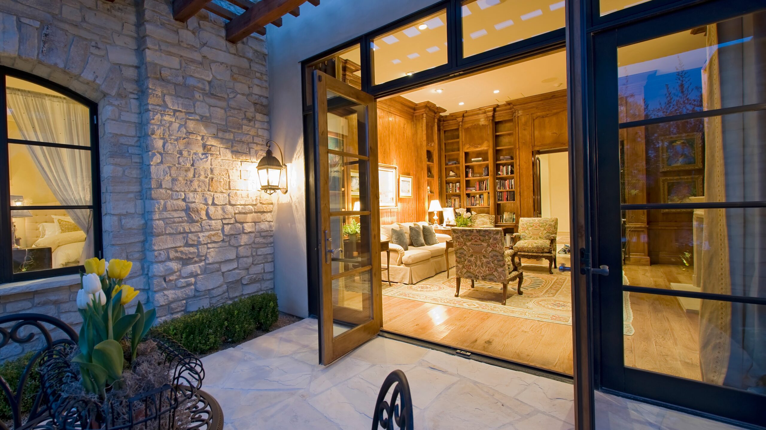 Angled view of an open pair of modernized French doors linking a living room to a flagstone patio with a pergola visible overhead