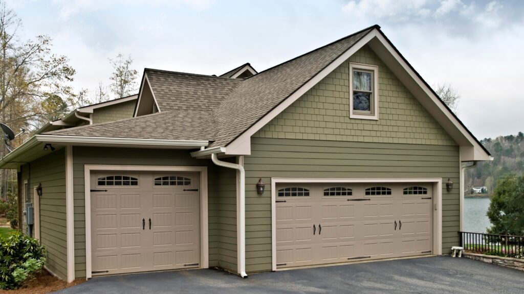 A wide view of the side of a suburban home clad in two shades of green Hardie Board in two different styles