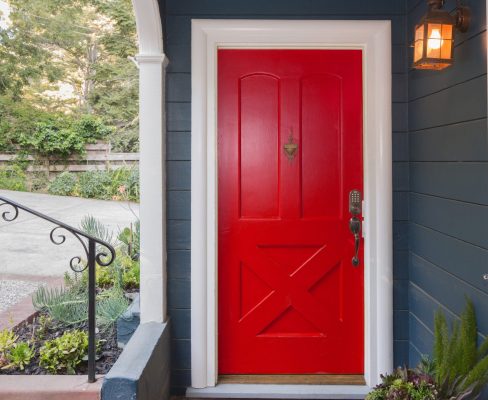 Close view of a bright red front door on a blue house