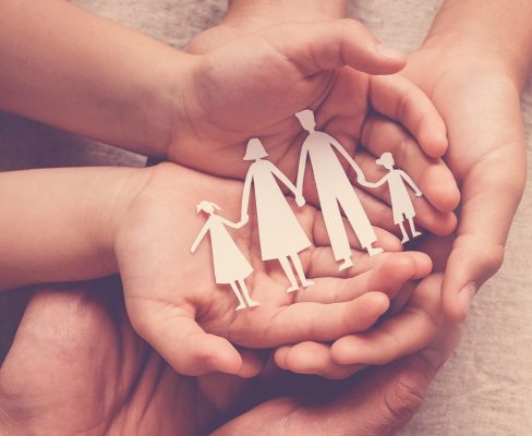 Adult and child's hands holding family cutouts - promoting safe, durable roofing solutions