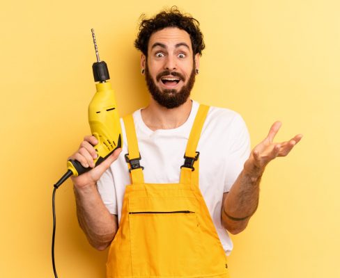 A confused handyman stands with a power drill