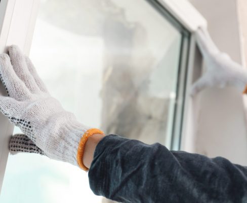 A window contractor installs a replacement window wearing white gloves