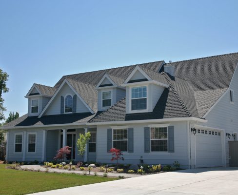 There is a large home with a fresh gray roof